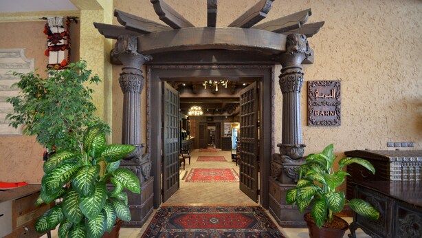 A grand entrance with a carpeted hallway, ornate columns, and potted plants. - Karan Sharq for Hotel Apartments Company (Al Jubail)