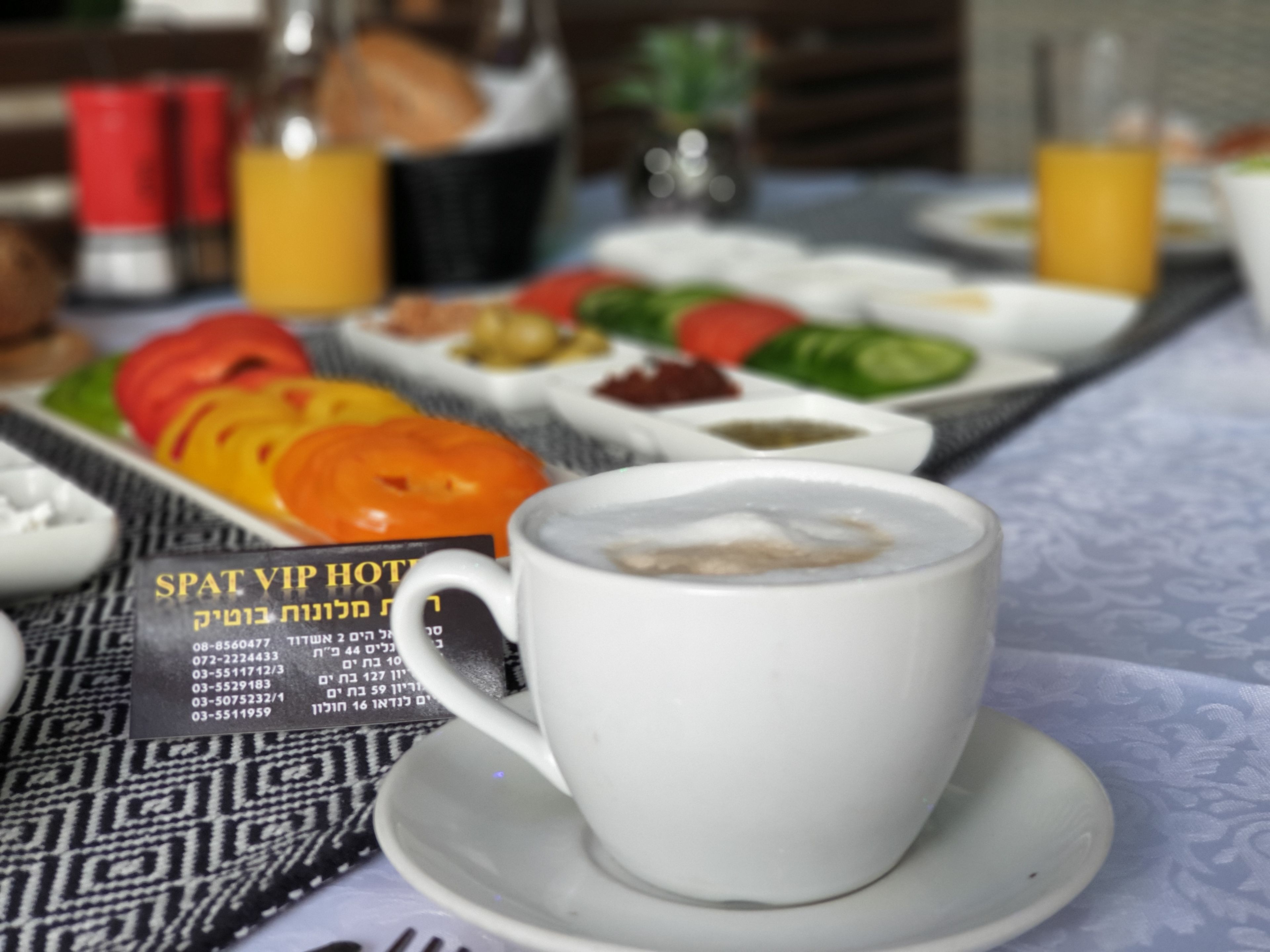 A breakfast table with a cup of coffee, a menu, and various food items.