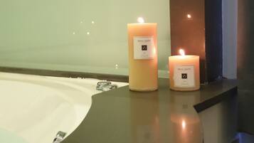 Dos velas encendidas sobre una encimera cerca de una bañera.