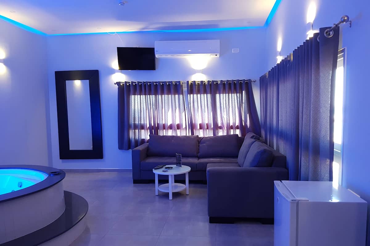 A modern living room with a sofa, a coffee table, a TV, and a hot tub.