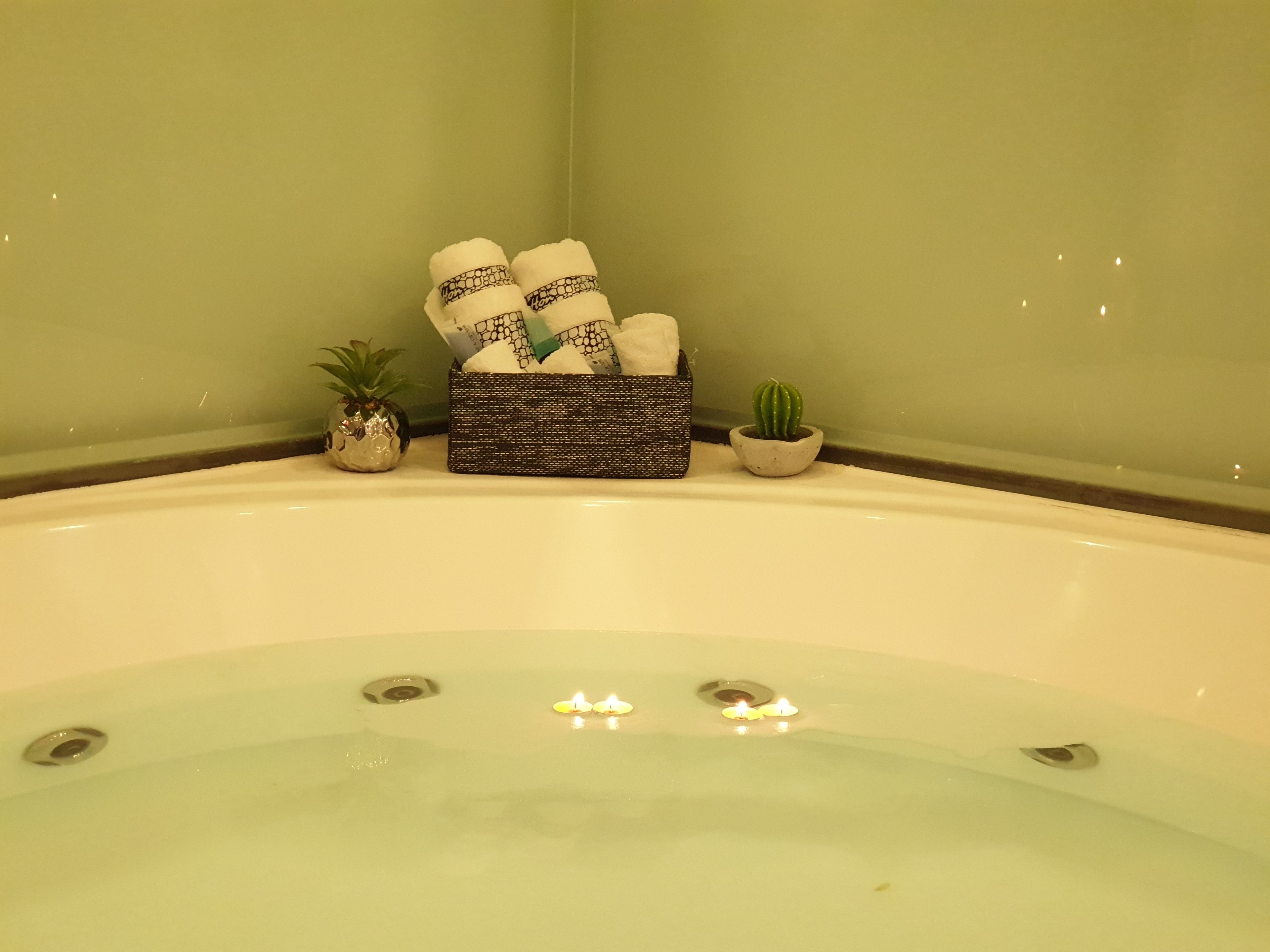 A bathtub with a decorative box containing towels and a small potted plant.