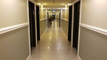 A long, well-lit hallway with doors on both sides, leading to rooms.