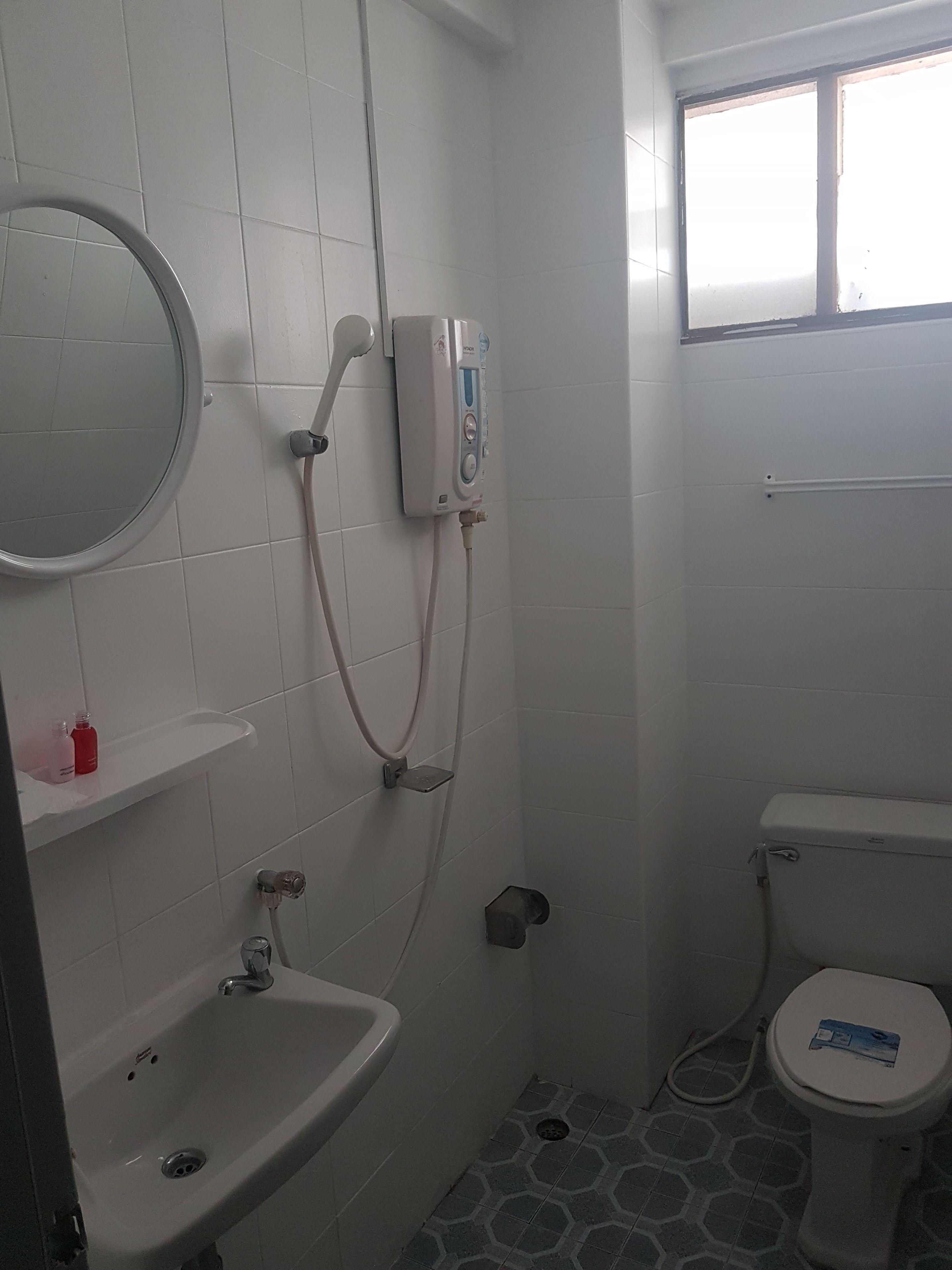 A small bathroom with a toilet, sink, and shower.