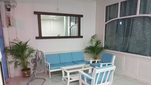 A room with a white sofa, two white chairs, a small table, and two potted plants. - Chaam Guesthouse (Cha-am)