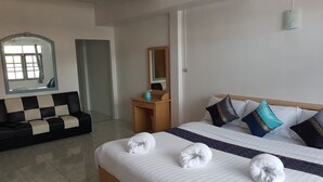 A hotel room with a bed, a sofa, a desk, a mirror, and a window. - Chaam Guesthouse (Cha-am)