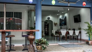 A hotel lobby with a reception desk, seating area, and a TV mounted on the wall. - Chaam Guesthouse (Cha-am)