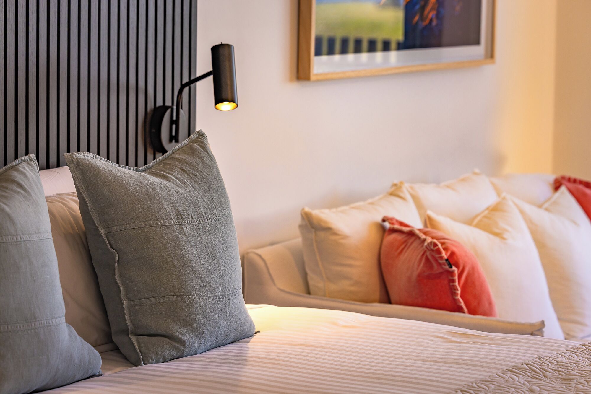 A bed with pillows, a bedside lamp, and a framed picture on the wall.