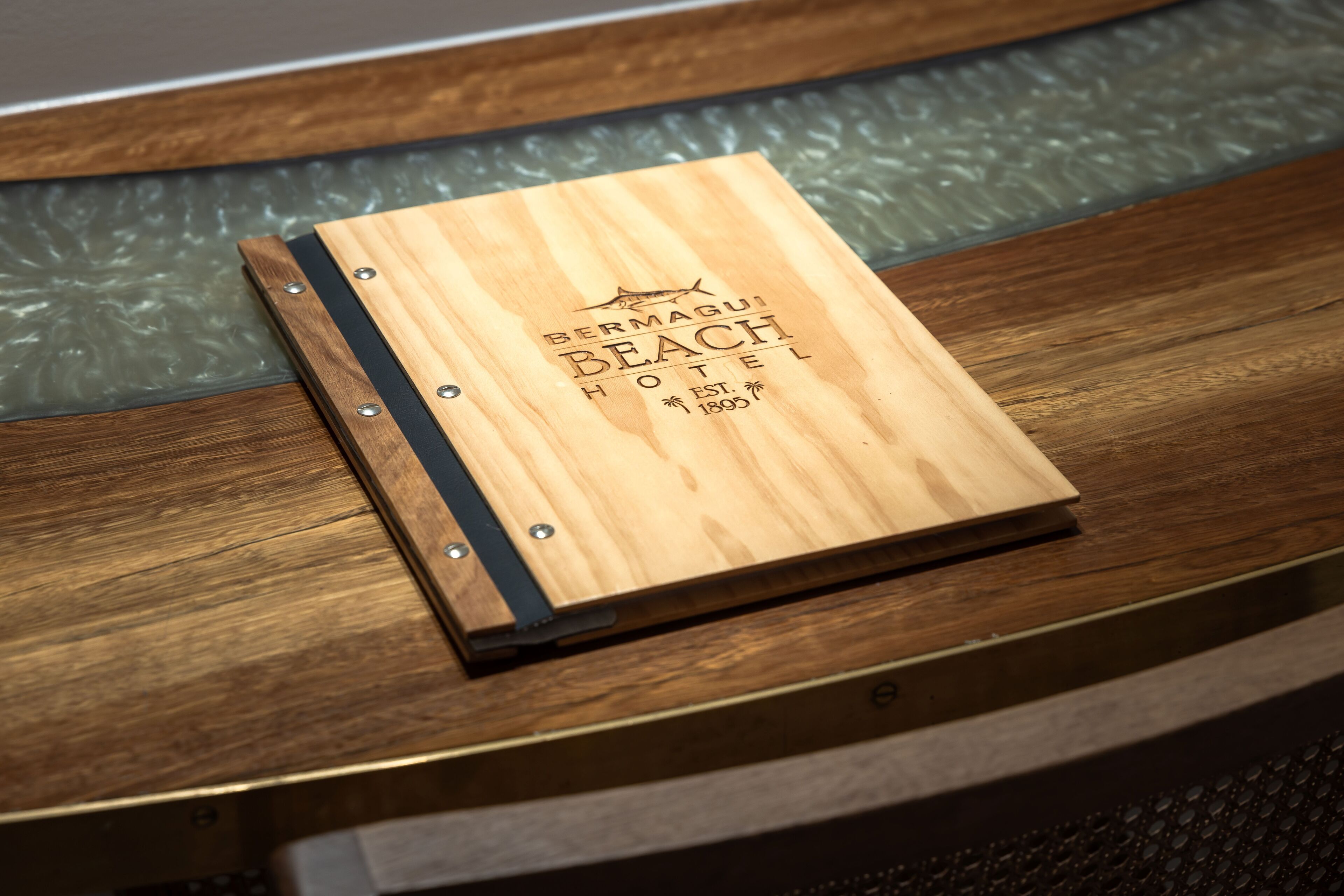 A wooden plaque with the text "Bermagui Beach Hotel" and "EST. 1895" on a wooden surface.
