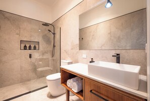 Enjoy a clean and uncluttered bathroom with a sleek vanity, large sink, and separate shower area.
