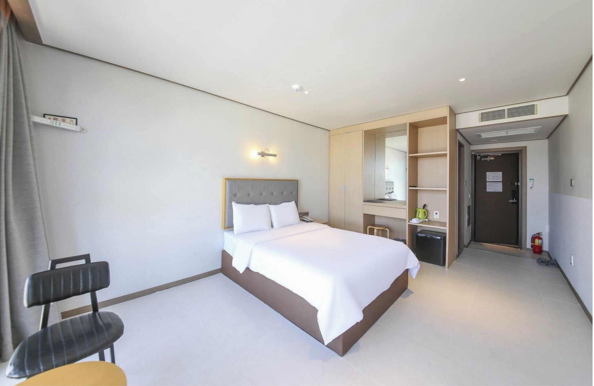 Une chambre d’hôtel comprenant un lit, un bureau, une chaise, une armoire et une salle de bain.