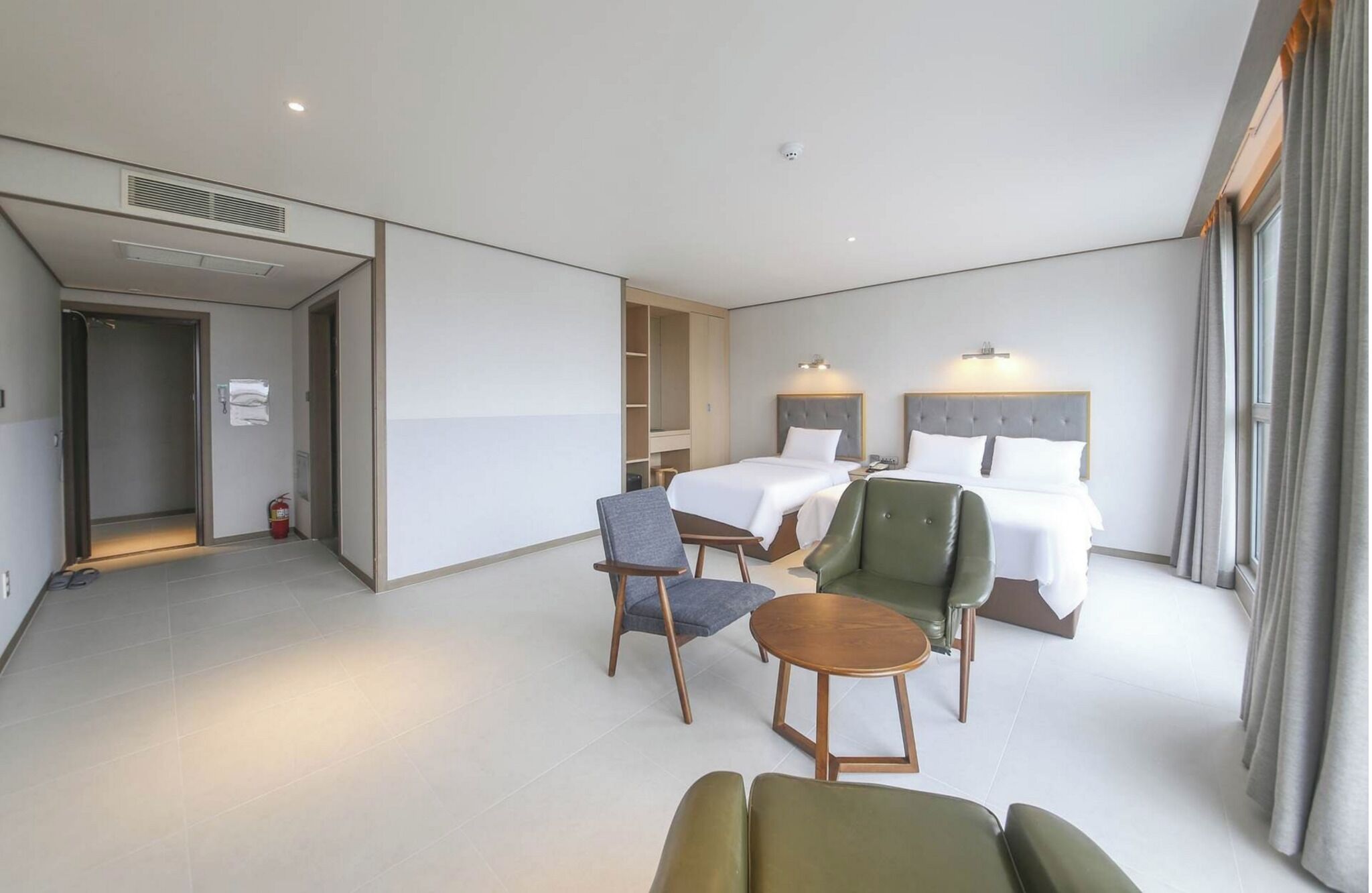 A hotel room with a bed, two chairs, a small table, and a wardrobe.