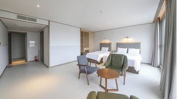 A hotel room with a bed, two chairs, a small table, and a wardrobe.