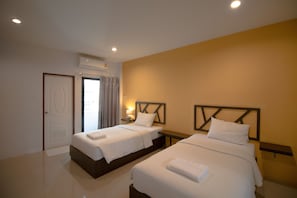 Quarto de hotel com duas camas, uma mesa de cabeceira, um ar condicionado e uma porta.