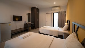 A hotel room with two beds, a desk, a TV, and an air conditioning unit. - Somsamai Style Apartment (Khon Kaen)