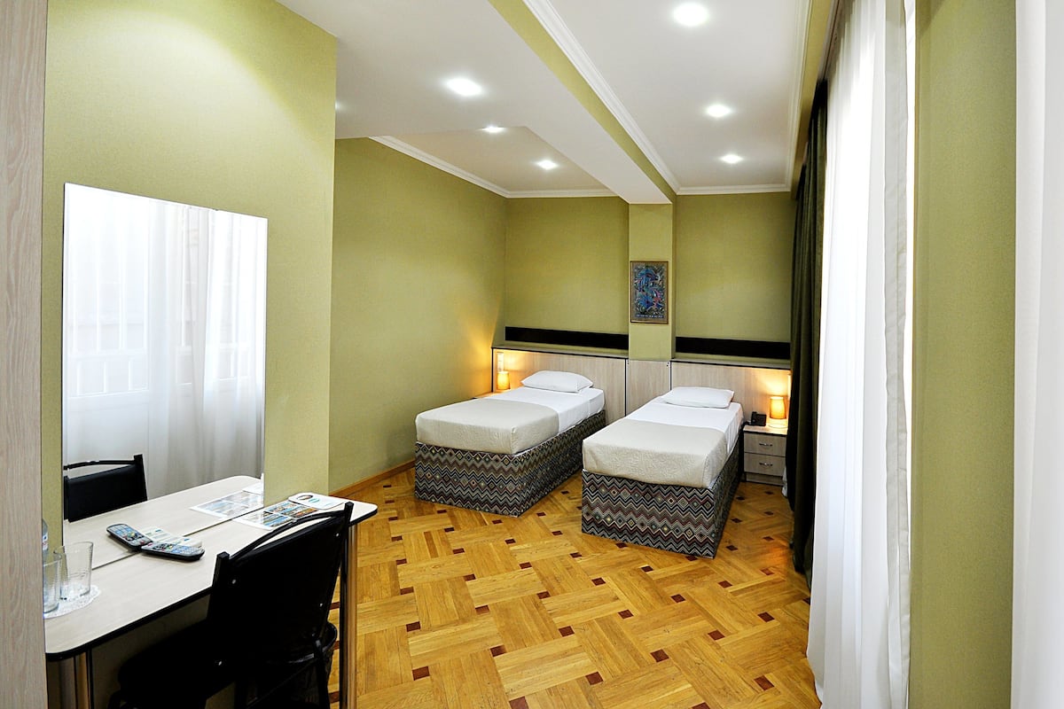 Una habitación con dos camas, una mesa, sillas y un escritorio pequeño con una silla.