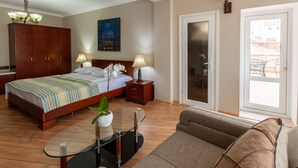 A bedroom with a bed, bedside tables, a nightstand, a sofa, a glass coffee table, a potted plant, a painting, and a sliding glass door leading to a balcony. - Hotel Penthouse (Tbilisi)