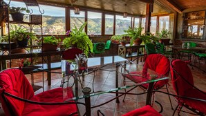 A spacious patio with red chairs and tables, surrounded by potted plants and a view of a valley. - Hotel Penthouse (Tbilisi)
