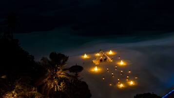 Vista noturna de um resort com tendas iluminadas e palmeiras.