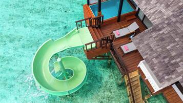 An aerial view of a resort with a pool, a slide, and wooden deck areas.