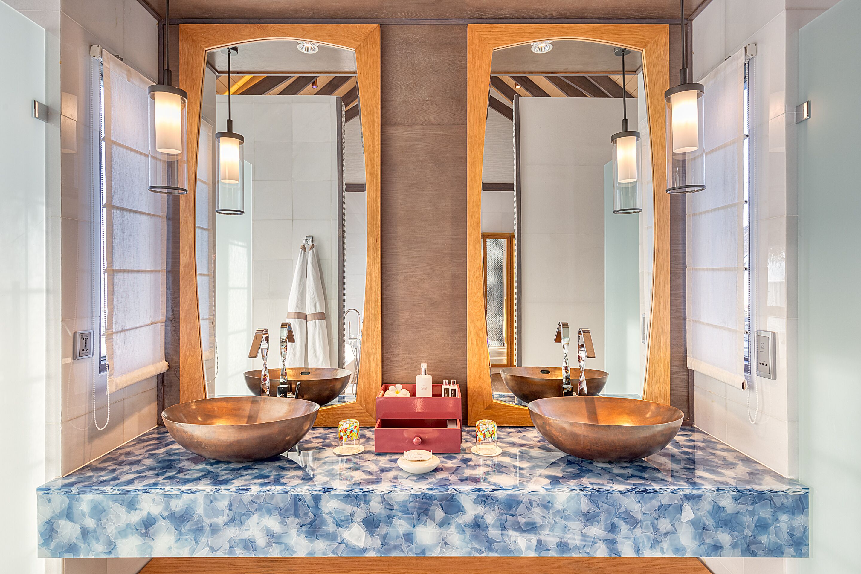 A bathroom with two large copper sinks, a wooden vanity, and a mirror cabinet.