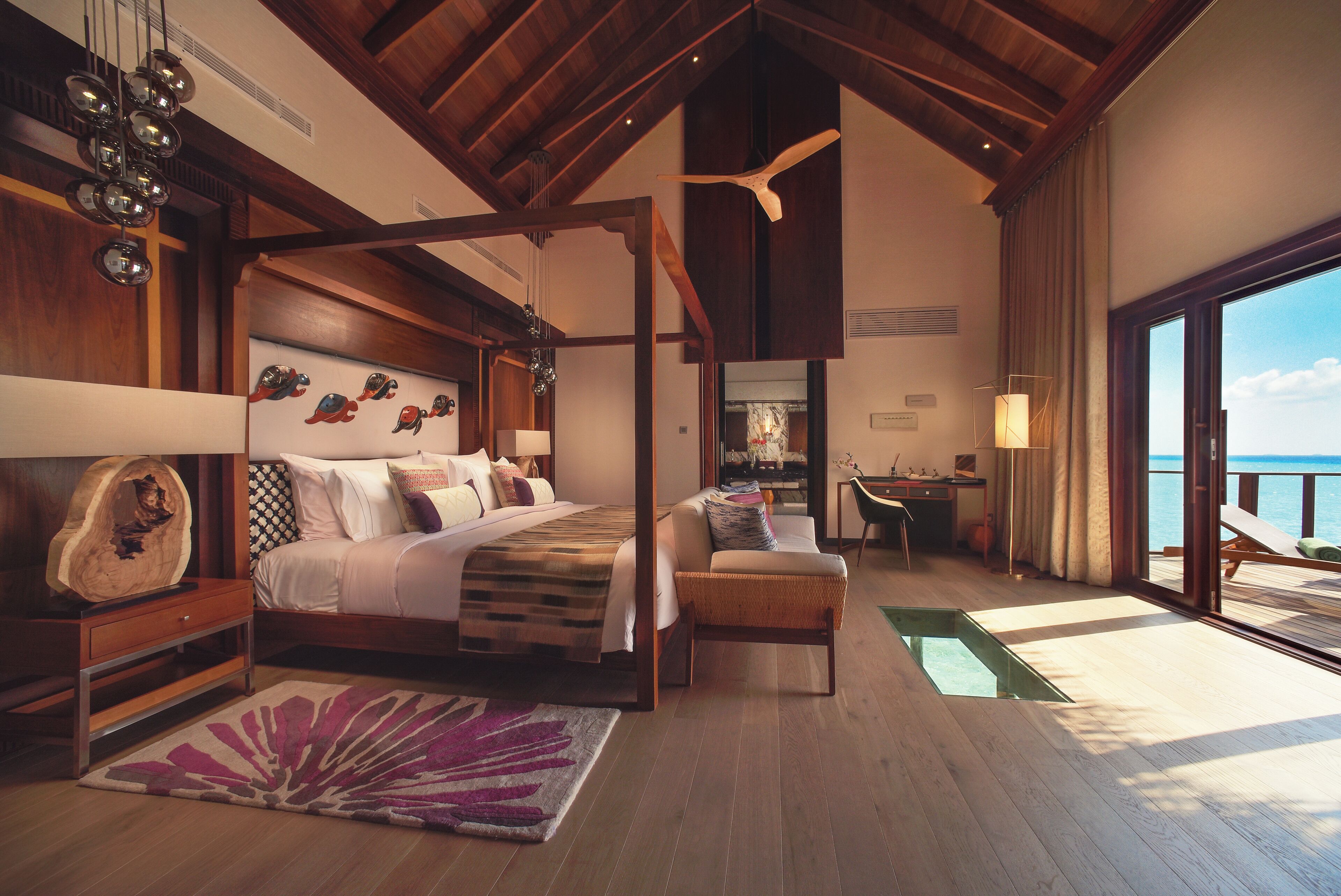 A spacious bedroom with a large bed, a sitting area, and a view of the sea.