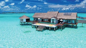 Overwater bungalows with thatched roofs, wooden decks, and glass railings, connected by a floating walkway. - OZEN LIFE MAADHOO - Luxury All Inclusive with Free Transfers (Maadhoo)