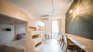 A modern, compact room with a bunk bed, a desk, and a chair. There is a small table and a shelf unit. - Hotel Axas Nihonbashi (Tokyo)
