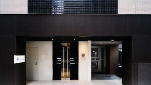 A hotel entrance with a modern design, featuring a black and white color scheme, a glass door, and a signboard. - Hotel Axas Nihonbashi (Tokyo)