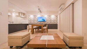 A modern living room with a wooden coffee table, beige sofas, and a flat-screen TV mounted on the wall. - Hotel Axas Nihonbashi (Tokyo)