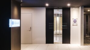 A modern hotel lobby with a reception desk, a glass door entrance, and a sign indicating the hotel name. - Hotel Axas Nihonbashi (Tokyo)