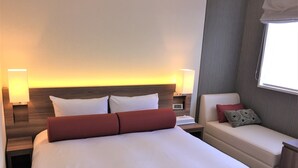 A hotel room with a large bed, two bedside tables, a nightstand, a sofa, and a window with curtains. - West Inn Fuji-Yoshida (Fujiyoshida)