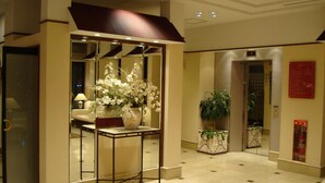 A lobby with a reception desk, a potted plant, and a wall-mounted clock. - West Inn Fuji-Yoshida (Fujiyoshida)
