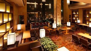A spacious lobby with multiple seating areas, a bar, and a large staircase. - Hotel New Omi (Omihachiman)