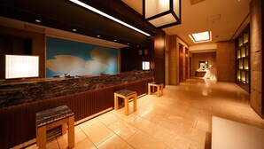 A hotel reception area with a marble counter, wooden stools, and a large abstract mural. - Hotel New Omi (Omihachiman)