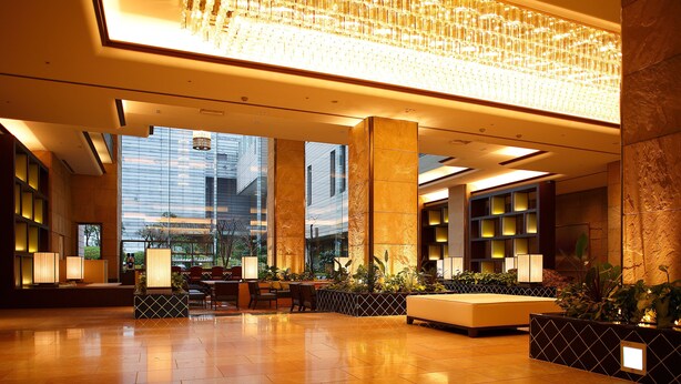 A spacious lobby with a large chandelier, seating areas, and a view of the cityscape through large windows. - Hotel New Omi (Omihachiman)