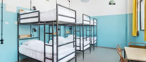 A dormitory room with bunk beds, a desk, and chairs.