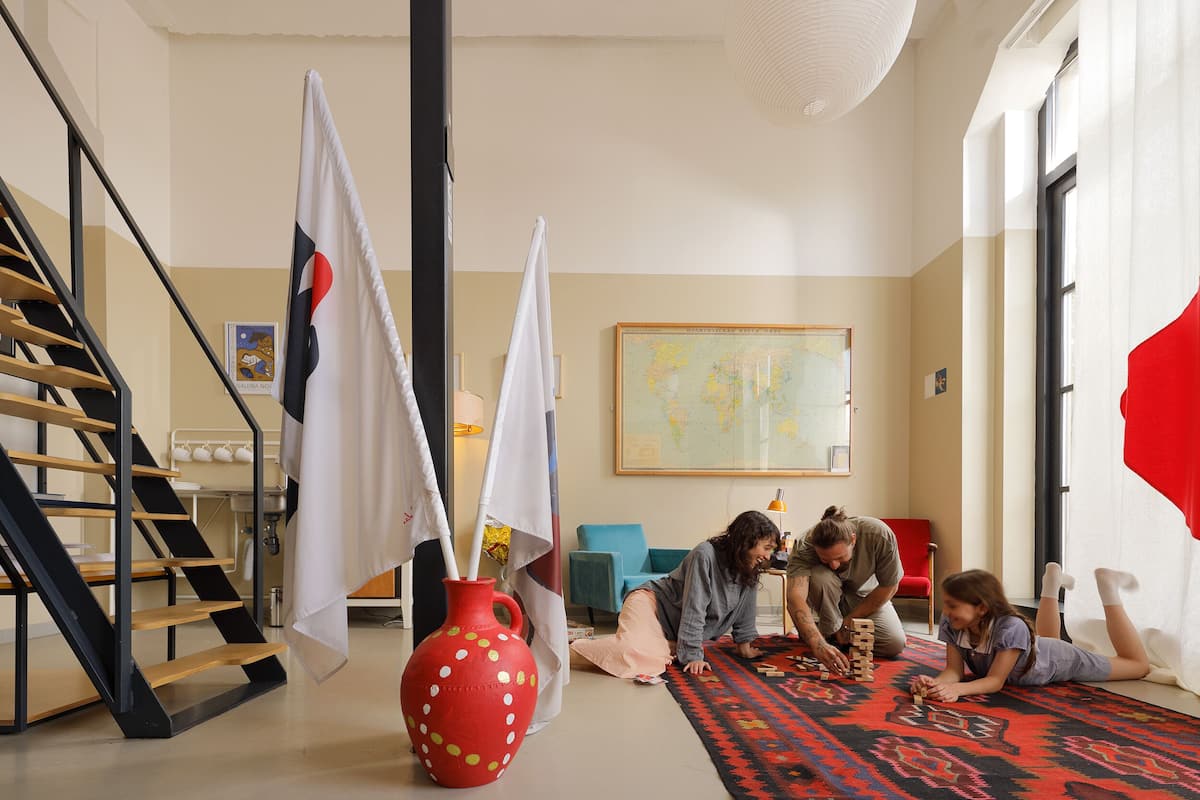 Ein Zimmer mit Treppe, einer großen roten Vase und einer Karte an der Wand.