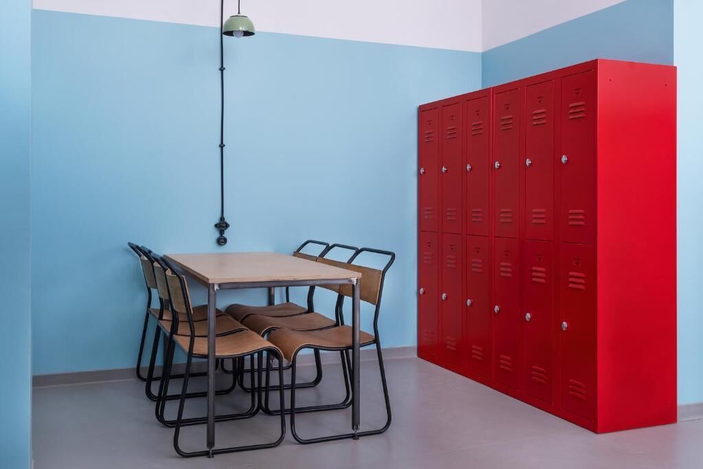 Een kamer met een tafel, stoelen, een rode kast en een hanglamp.