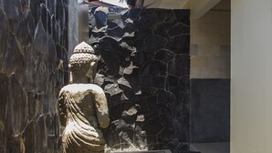 Eine Steinstatue in einem Raum mit einer Steinwand und einem Fliesenboden.