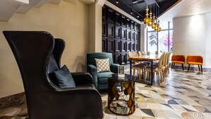 A modern interior with a black leather armchair, teal sofa, and orange chairs around a wooden dining table. - Norway Forest Travel Hotel 3 Taichung (Taichung)