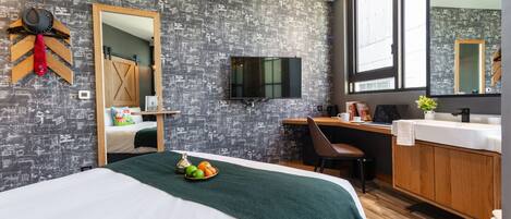 A hotel room with a large bed, a desk, a TV, and a bathroom with a wooden cabinet.