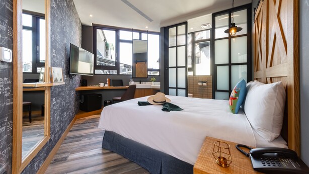 A modern hotel room with a large bed, a desk, a TV, and a bathroom visible through a glass door. - Norway Forest Travel Hotel 3 Taichung (Taichung)