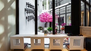 A modern interior with a dining area featuring a white table and chairs, a large window with a view of the city, and decorative wall-mounted lights. - Norway Forest Travel Hotel 3 Taichung (Taichung)