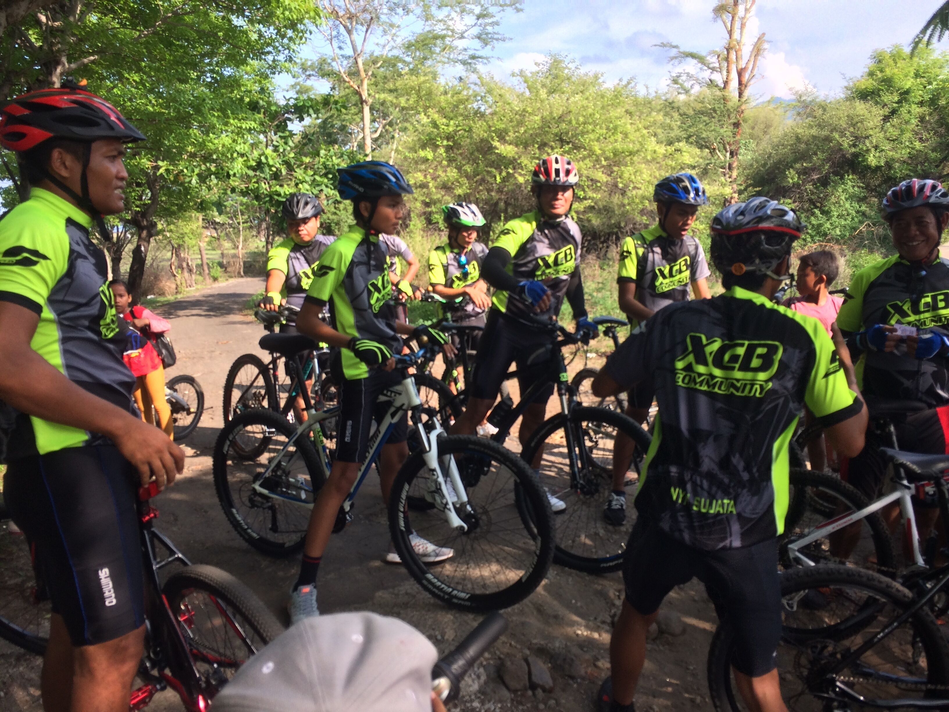 A group of cyclists in a forested area with bicycles and helmets.