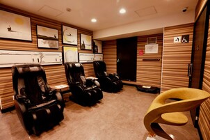 Una sala de masajes con dos camillas, un revestimiento de madera con obras de arte y un cartel de accesibilidad para sillas de ruedas.