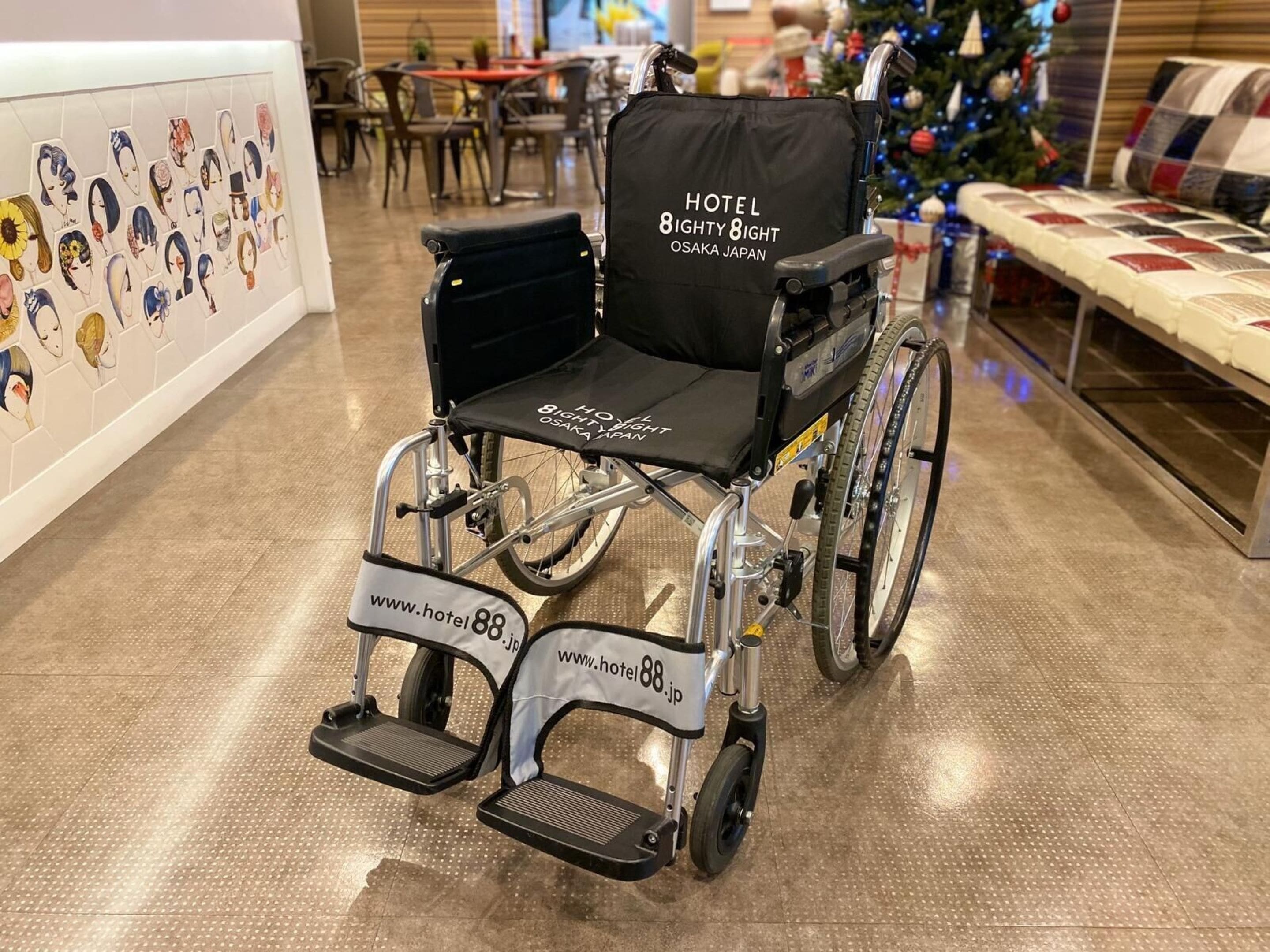 A wheelchair with a black seat and backrest, labeled "HOTEL 8IGHTY 8IGHT OSAKA JAPAN" and website "www.hotel88.jp".