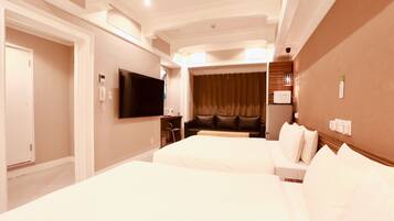 Habitación de hotel con dos camas, televisión, escritorio y cortina.