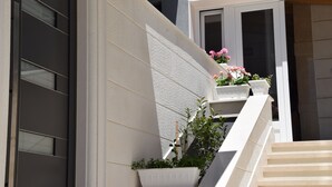 Un edificio moderno con una escalera que conduce a un balcón con plantas y flores en macetas.