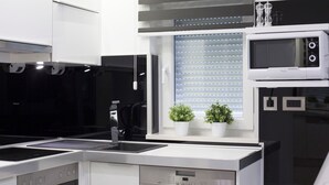 Una cocina moderna con estufa negra, microondas y ventana con persianas.