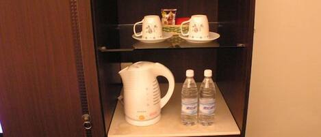 A hotel minibar with a coffee maker, two bottles of water, and a tea set.